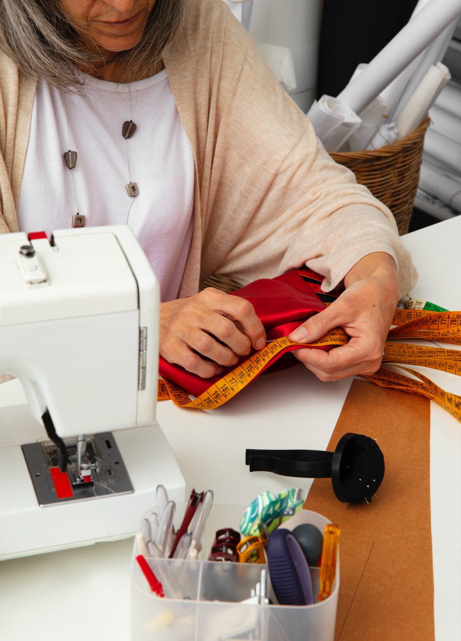 Créatrice en plein travail dans son atelier, utilisant une machine à coudre pour assembler des tissus recyclés colorés. Scène illustrant le processus artisanal et local de fabrication des pochettes ÉTOFÉ.