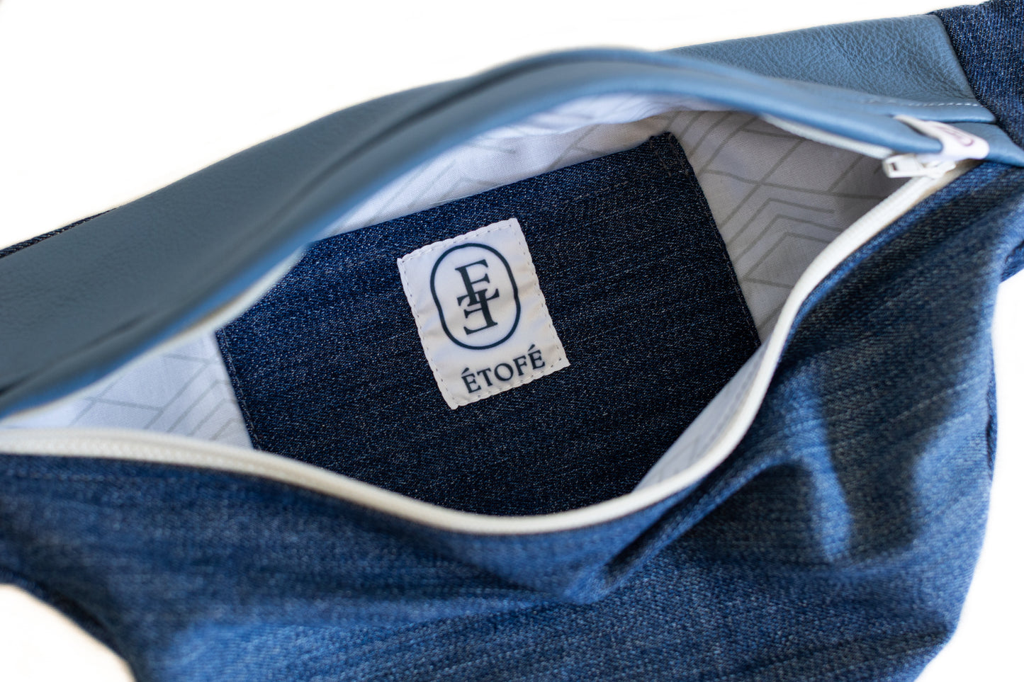 Vue rapprochée de l'intérieur d'une banane en jean recyclé Étofé avec fermeture éclair blanche et doublure géométrique claire