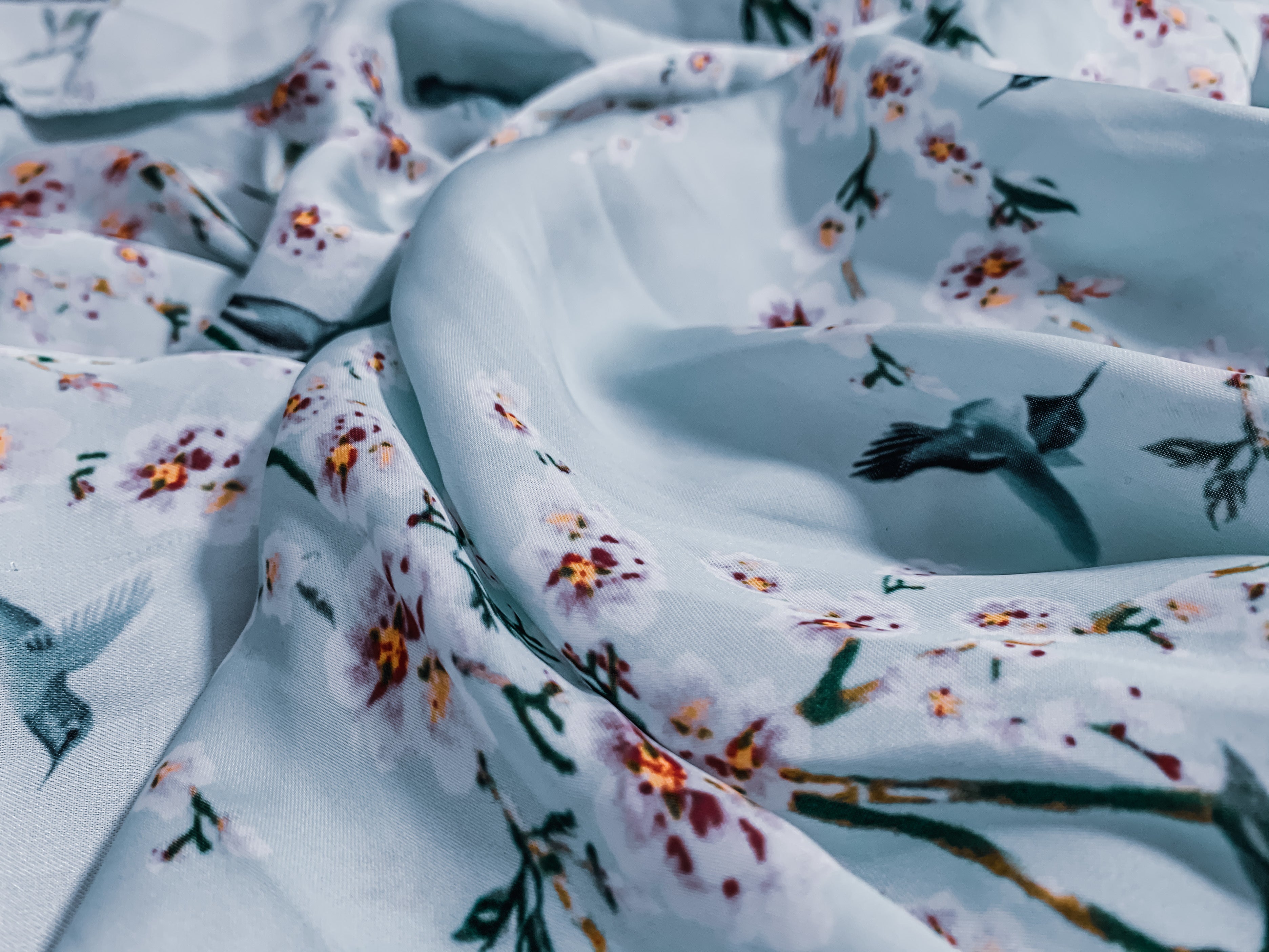 Gros plan sur un drap en tissu fleuri haut de gamme, illustrant l’élégance des textiles d’hôtellerie de luxe, idéal pour une transformation ÉTOFÉ en accessoire unique et raffiné.