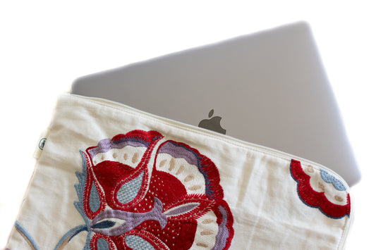 Housse upcyclée en tissu brodé de fleurs rouges, contenant un MacBook – création artisanale écoresponsable.