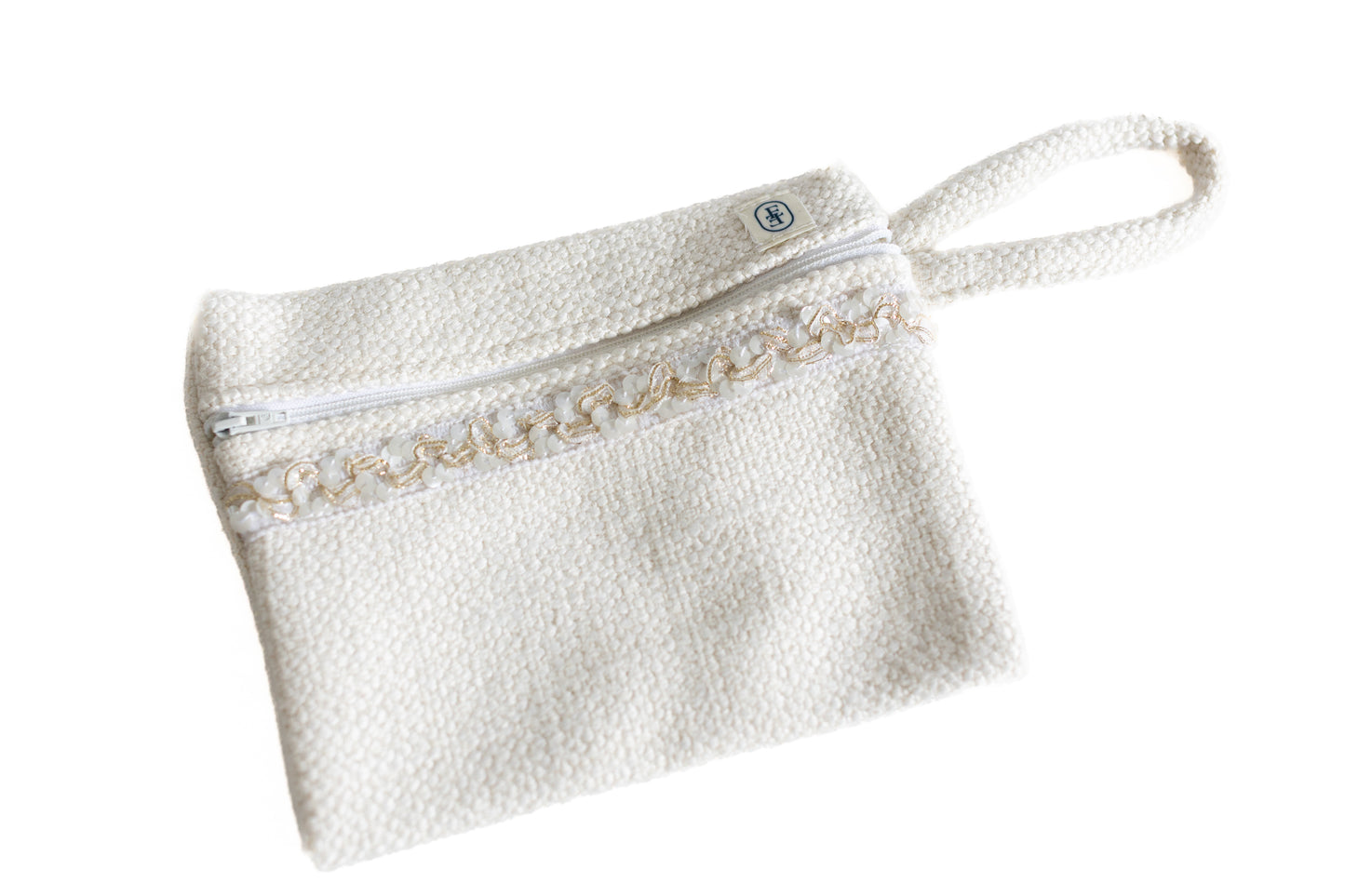 Pochette plate ÉTOFÉ blanche en tissu bouclette, décorée d’un galon blanc et doré, avec une petite poignée pratique assortie.