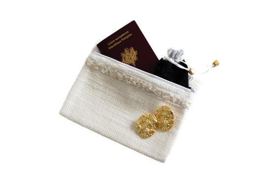 Pochette plate ÉTOFÉ blanche en tissu bouclette, ornée d’un galon doré et contenant un passeport et une petite pochette noire.