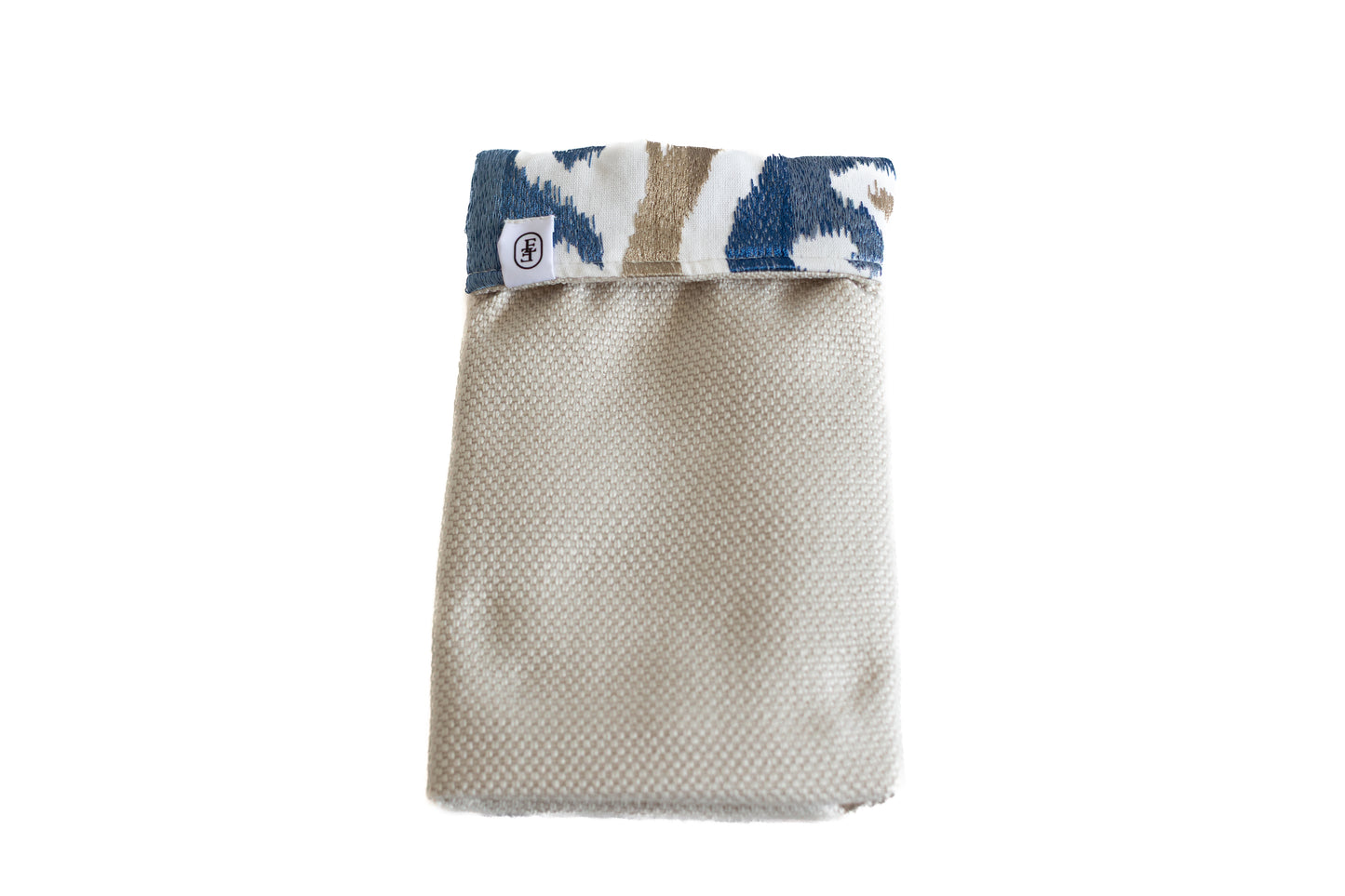 Pochette ÉTOFÉ en tissu beige texturé, avec un revers à motifs graphiques bleu marine et beige, confectionnée localement à partir de tissus d’ameublement recyclés.