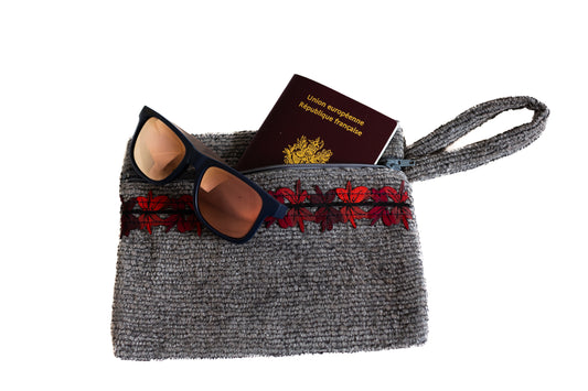 Pochette plate ÉTOFÉ grise en tissu upcyclé, galon brodé rouge foncé, contenant un passeport français et des lunettes de soleil, avec fermeture éclair et dragonne assortie.