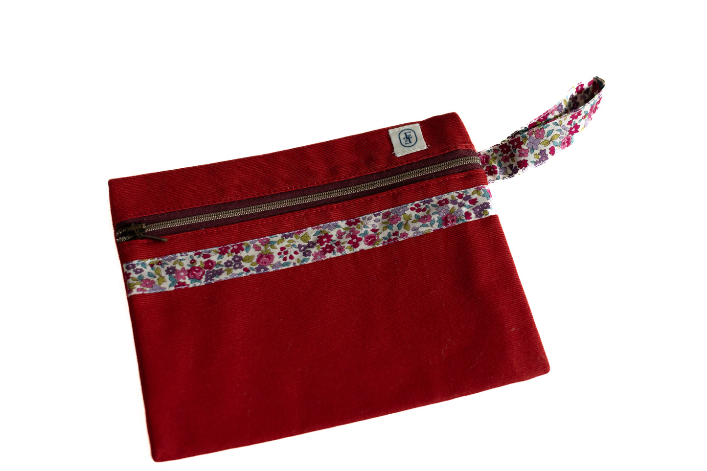 Pochette plate ÉTOFÉ en tissu rouge upcyclé, décorée d’un galon fleuri type Liberty et d’une fermeture zippée, avec poignée assortie.