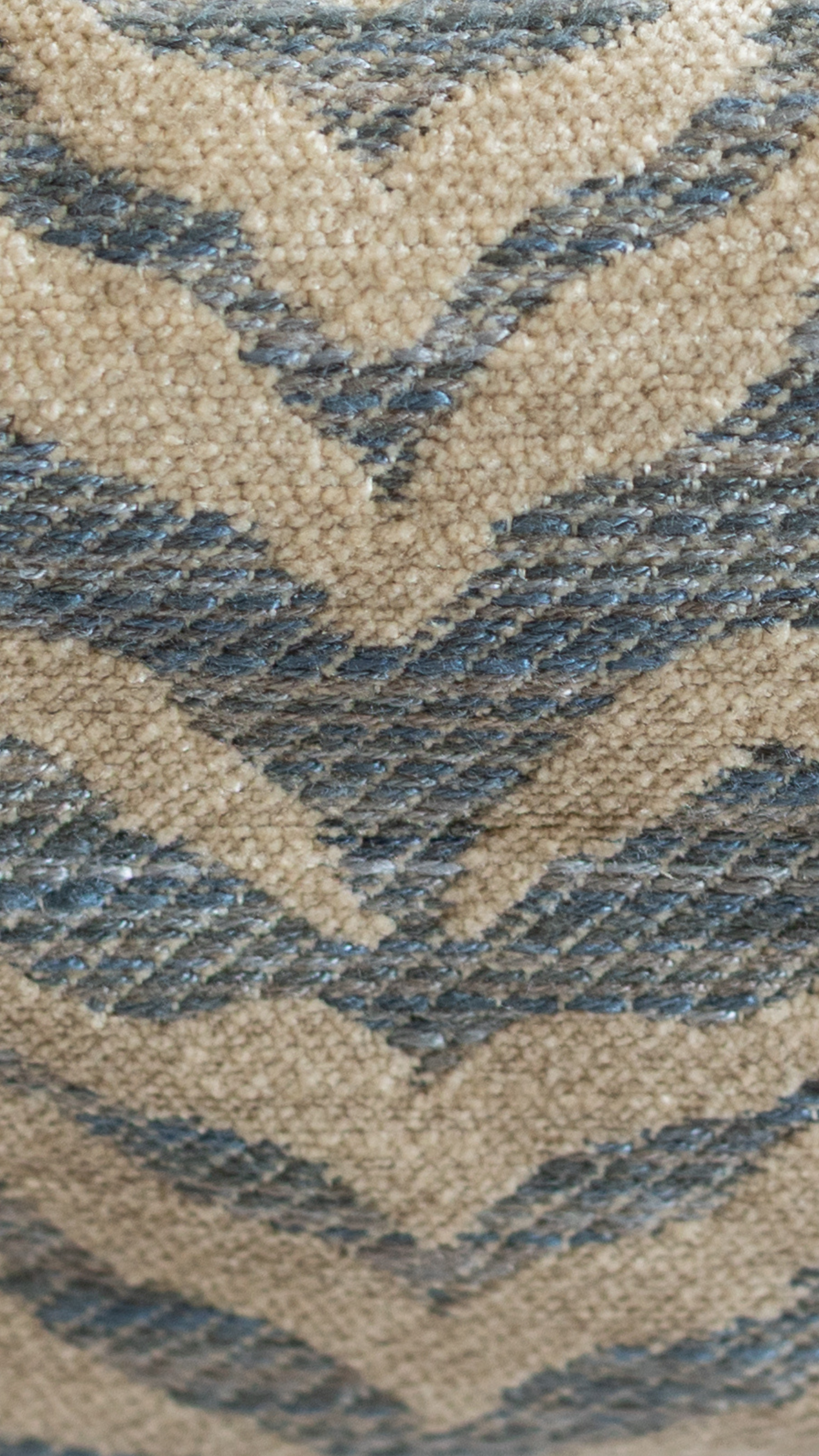 Gros plan sur un tissu à motif chevron bleu et beige, texture épaisse et upcyclée.