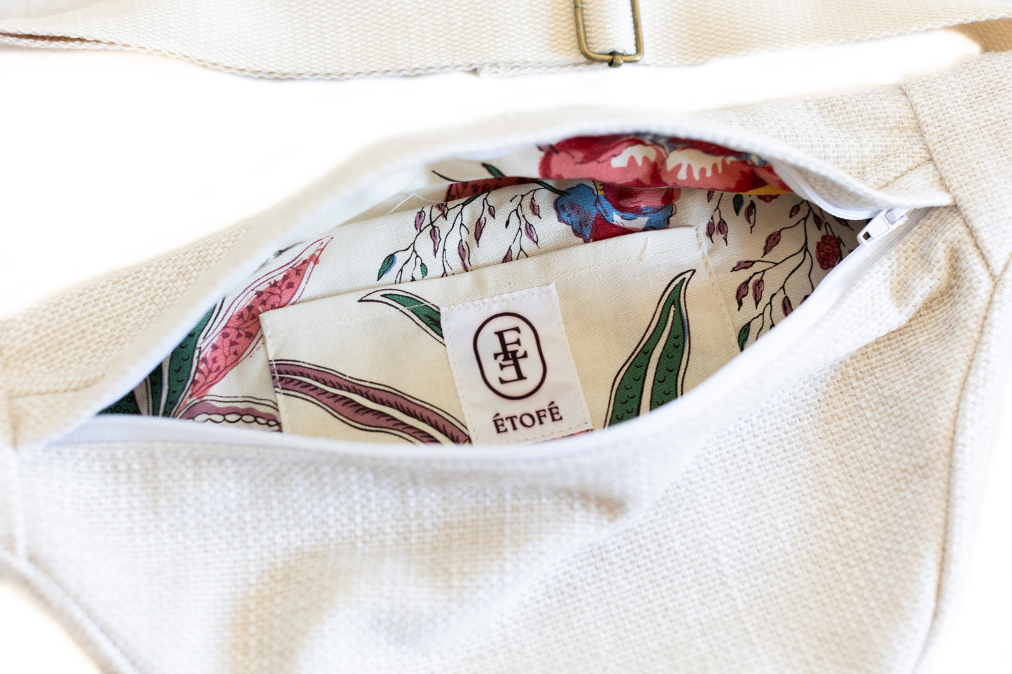 Zoom sur banane blanche en tissu bouclé avec intérieur fleuri et fermeture éclair blanche, vue de l’intérieur – Étofé