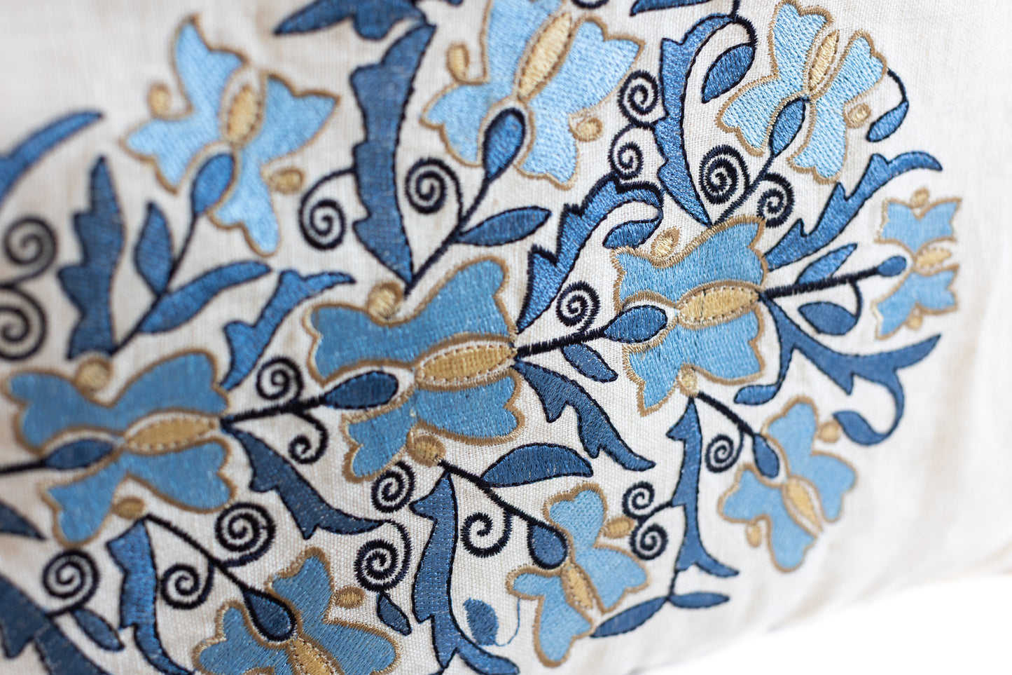 Zoom sur une broderie florale bleue et beige réalisée sur un tissu recyclé, illustrant le savoir-faire artisanal d'ÉTOFÉ.