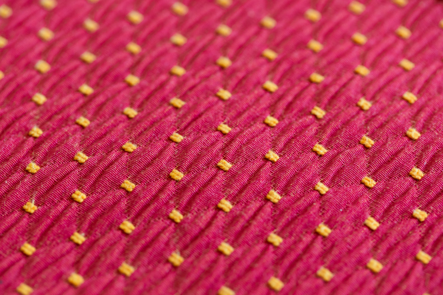 Gros plan sur un tissu rouge à motifs jaunes utilisé pour les sacs ÉTOFÉ, illustrant le détail du tissage et la qualité du tissu recyclé.