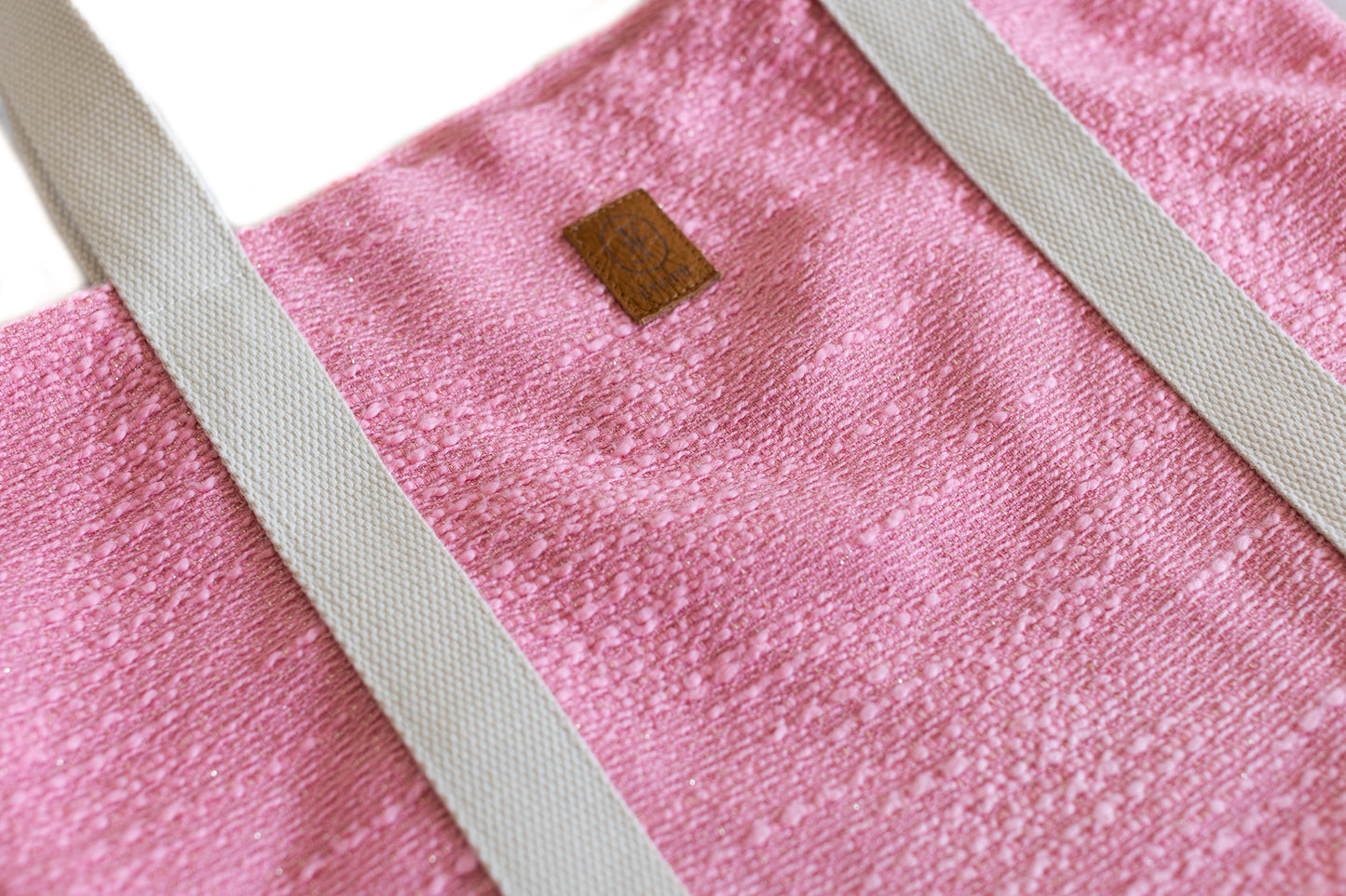 Gros plan sur le tissu rose du sac cabas ÉTOFÉ, étiquette en cuir marron et anses écrues.