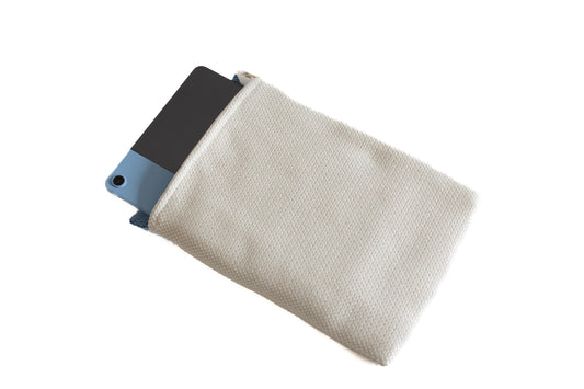 Pochette beige en tissu recyclé contenant une tablette. Accessoire artisanal conçu avec soin sur la Côte d’Azur à partir de matières revalorisées.