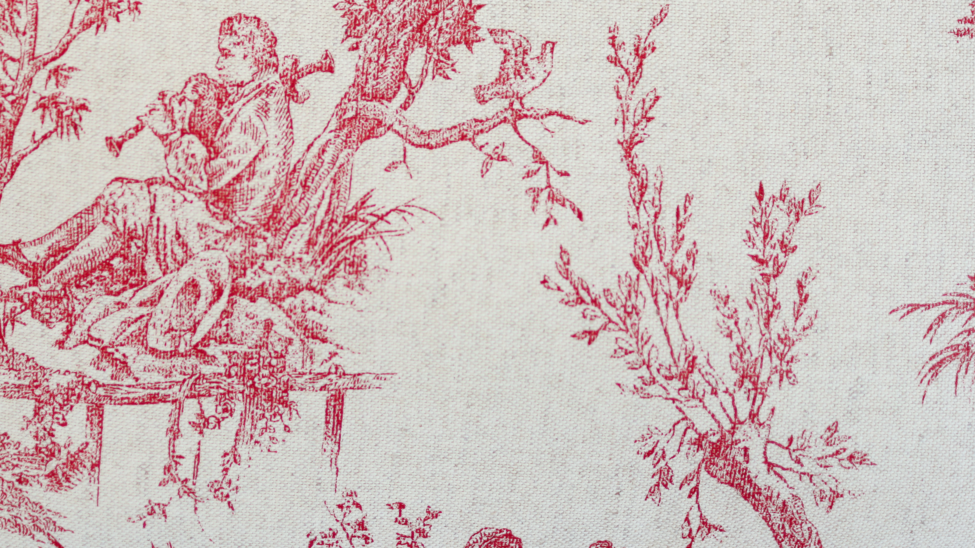 Gros plan sur un tissu toile de Jouy rouge représentant une scène de campagne avec un musicien jouant de la flûte, utilisé dans les créations d’accessoires ÉTOFÉ.